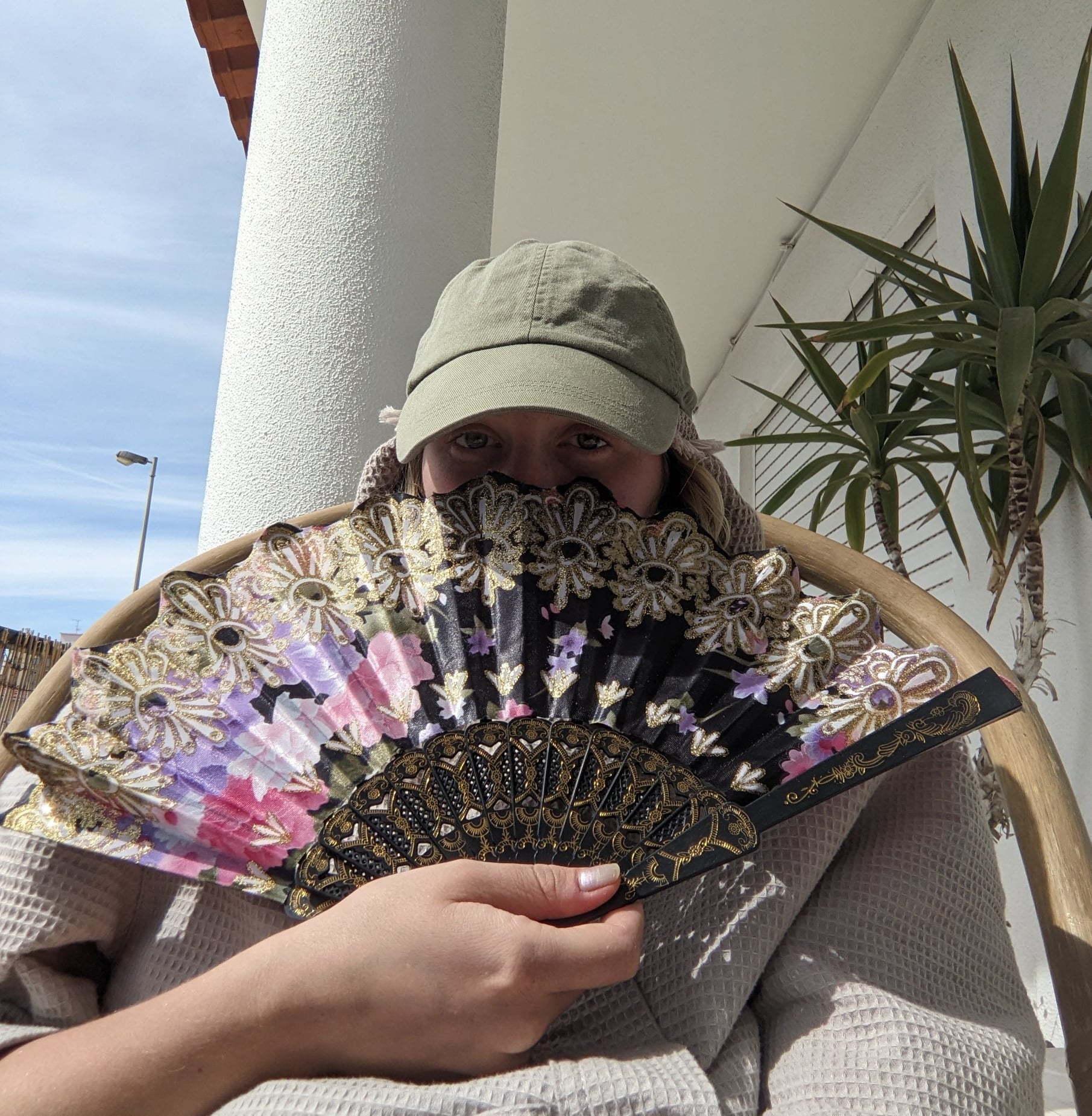 profile picture of a person with a green hat holding a fan
